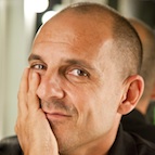 Close up headshot of comedian Carl Barron as he leans his head on his hand.